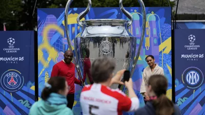 People take pictures at a giant trophy during the opening of the official UEFA fan festival in Munich, Germany, Thursday, May 29, 2025 ahead of the Champions League final soccer match between Inter and PSG. (AP Photo/Matthias Schrader)