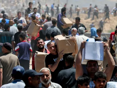 Palestinians carry aid supplies which they received from the U.S.-backed Gaza Humanitarian Foundation, in the central Gaza Strip, May 29, 2025. REUTERS/Ramadan Abed REFILE - CORRECTING LOCATION FROM "NEAR AN AREA OF GAZA KNOWN AS THE NETZARIM CORRIDOR" TO "IN THE CENTRAL GAZA STRIP".