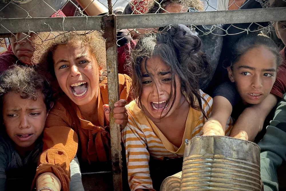 25 May 2025, Palestinian Territories, Khan Yunis: Palestinians wait in long queues to receive pots of food distributed by charitable organizations, as they face food crisis, in Al-Mawasi area in Khan Yunis, Gaza strip on May 25, 2025. Food crisis in the Gaza Strip deepens day by day as Israel continues block aid entries. Photo: Moaz Abu Taha/APA Images via ZUMA Press Wire/dpa