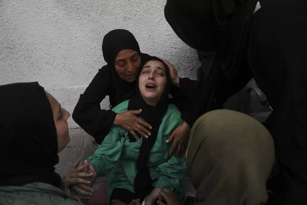 Walaa Al-Kilani, center, mourns her mother and brother, who were killed when an Israeli military strike hit a school sheltering displaced residents, at Al-Shifa Hospital in Gaza City, Monday, May 26, 2025. (AP Photo/Jehad Alshrafi)