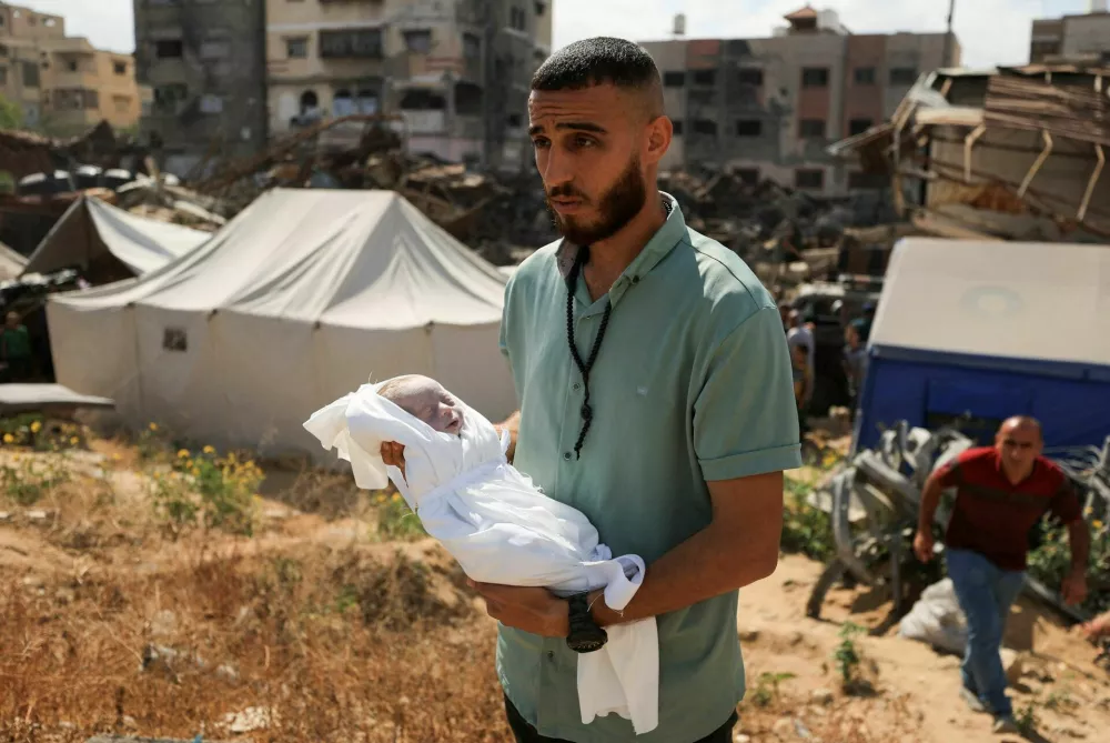 SENSITIVE MATERIAL. THIS IMAGE MAY OFFEND OR DISTURB A Palestinian mourner carries the body of the stillborn baby of Palestinian woman Seham Al-Arabeed, who was killed in an a Israeli strike, according to medics, at a cemetery in Gaza City, May 28, 2025. REUTERS/Dawoud Abu Alkas REFILE - QUALITY REPEAT