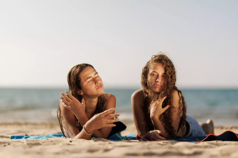 Two friends relaxing on a sandy beach under the sun, enjoying a peaceful and joyful day by the sea.