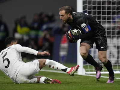 Atletico Madrid's goalkeeper Jan Oblak saves in front of Real Madrid's Jude Bellingham during the Champions League round of 16, second leg, soccer match between Atletico Madrid and Real Madrid at the Metropolitano stadium in Madrid, Spain, Wednesday, March 12, 2025. (AP Photo/Bernat Armangue)