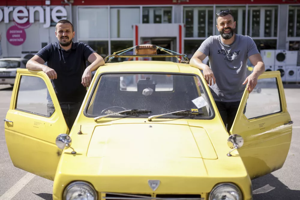 Tarik Fatic, left, and his brother Mirnes pose for a photo next to the Reliant Regal, an exact copy of the famous BBC TV show  "Only Fools and Horses" iconic yellow car in Hadzici, suburb of Sarajevo, Bosnia, Wednesday, June 4, 2025. (AP Photo/Armin Durgut)