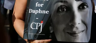 A person holds a placard depicting Daphne Caruana Galizia, prepared by Committee to Protect Journalists (CPJ), as people gather at the site where anti-corruption journalist was assassinated in a car bomb one year ago, in Bidnija, Malta October 16, 2018. REUTERS/Darrin Zammit Lupi - RC16E46980D0