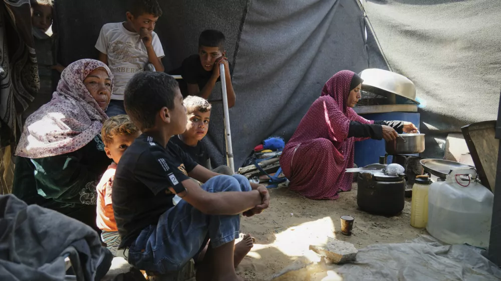 Tahreer Abu Jazar, 36, right, prepares an Eid al-Adha meal for her family inside their tent at a camp for displaced Palestinians in Mawasi Khan Younis, Gaza Strip, on Friday, June 6, 2025. (AP Photo/Abdel Kareem Hana)