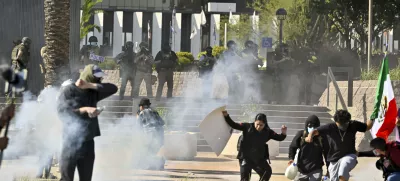 Protesters run from police as they use tear gas and flash-bangs at the Federal Building in Santa Ana, Calif., on Monday, June 9, 2025. (Jeff Gritchen/The Orange County Register via AP)