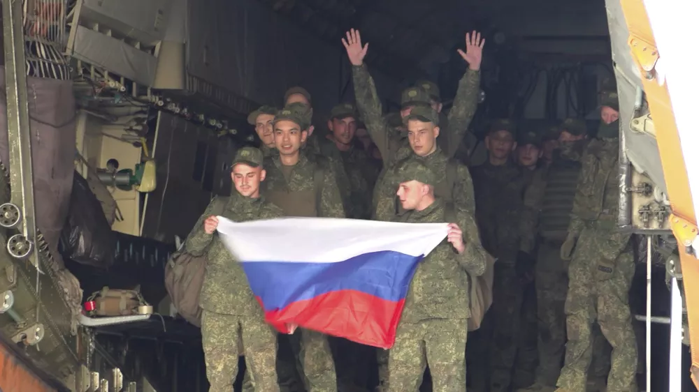 In this photo, taken from video and released by Russian Defense Ministry Press Service on Monday, June 9, 2025, Russian servicemen hold a Russian national flag as they leave a plane after returning from captivity by a POWs exchange of the first group of servicemen under 25 years of age between Russia and Ukraine, at an airport outside Moscow, Russia. (Russian Defense Ministry Press Service via AP)