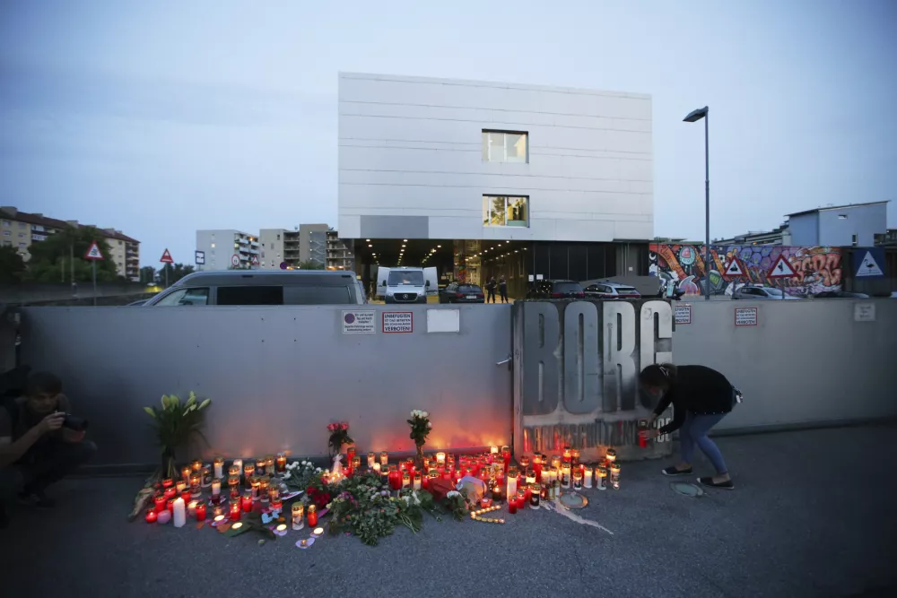 A woman places a candle at the entrance to a school after a deadly shooting took place there, in Graz, Austria, Tuesday, June 10, 2025. (AP Photo/Heinz-Peter Bader)