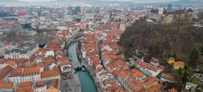 Panorama of Ljubljana city. Aerial view above Ljubljanica river with river cruise boats towards city center. Historical town with old architecture and the castle on the hill. Cloudy day in the winter. / Foto: Izvir8