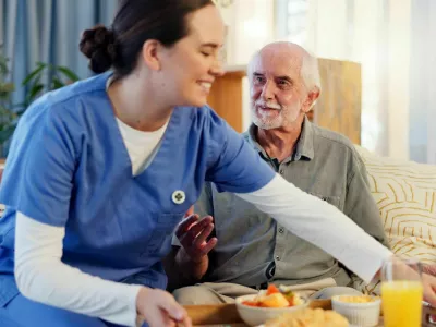 Breakfast, nurse and senior man in nursing home for elderly care, nutrition and support. Retired male person, caregiver and service for hungry patient in assisted living, healthcare and wellness / Foto: Jacob Wackerhausen
