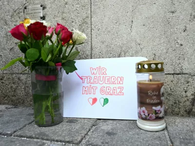 11 June 2025, Austria, Vienna: Candles and flowers are placed in front of St. Stephen's Cathedral in central Vienna, where a poster reads "We mourn with Graz," after a school rampage in Graz left eleven people dead. Photo: Helmut Fohringer/APA/dpa