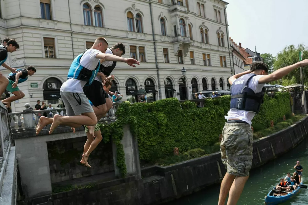 11.06.2025. Skupina mladeničev skače v Ljubljanico s Tromostovja. Vročinski val. Foto: Bojan Velikonja 