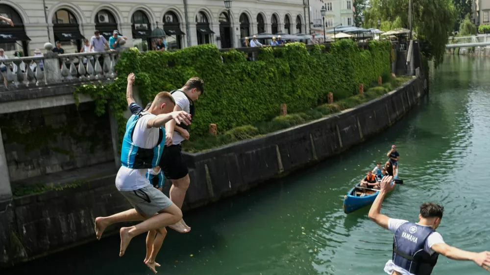 11.06.2025. Skupina mladeničev skače v Ljubljanico s Tromostovja. Vročinski val. Foto: Bojan Velikonja 