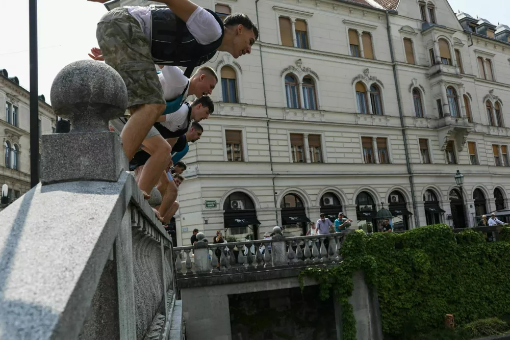 11.06.2025. Skupina mladeničev skače v Ljubljanico s Tromostovja. Vročinski val. Foto: Bojan Velikonja 
