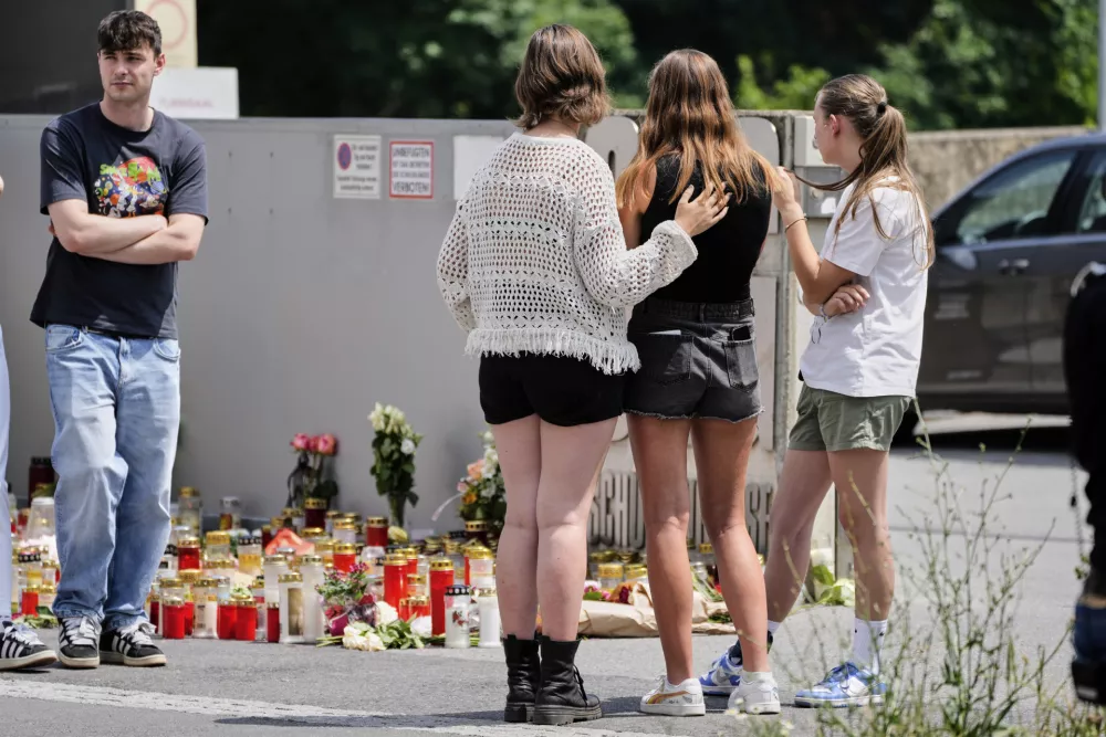 Students stand outside a school where a former student opened fire the day before fatally wounding several people and injuring many others before taking his own life, Graz, Austria, Wednesday, June 11, 2025. (AP Photo/Darko Bandic)