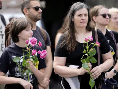 People pay a moment of silence on the main square after a former student opened fire the day before at a school fatally wounding several people and injuring many others before taking his own life, Graz, Austria, Wednesday, June 11, 2025. (AP Photo/Darko Bandic)