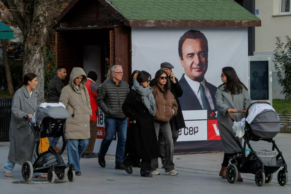 FILE PHOTO: Pedestrians walk near a campaign poster for the upcoming parliamentary elections showing a portrait of Albin Kurti, Kosovo's Prime Minister and leader of the Self-Determination party, in Pristina, Kosovo February 4, 2025. REUTERS/Valdrin Xhemaj/File Photo