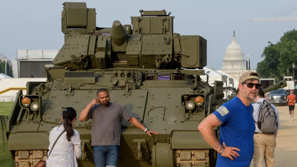 People pass by and take photos with a tank, parked on the National Mall, during preparations for an upcoming military parade commemorating the Army's 250th anniversary and coinciding with President Donald Trump's 79th birthday, Thursday, June 12, 2025, in Washington. (AP Photo/Rod Lamkey, Jr.)