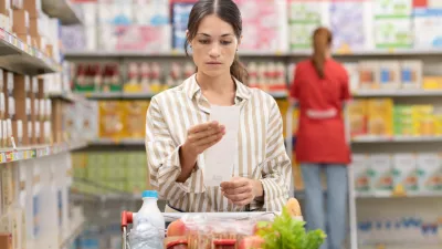 Woman checking a long grocery receipt at the supermarket, grocery shopping and budget concept