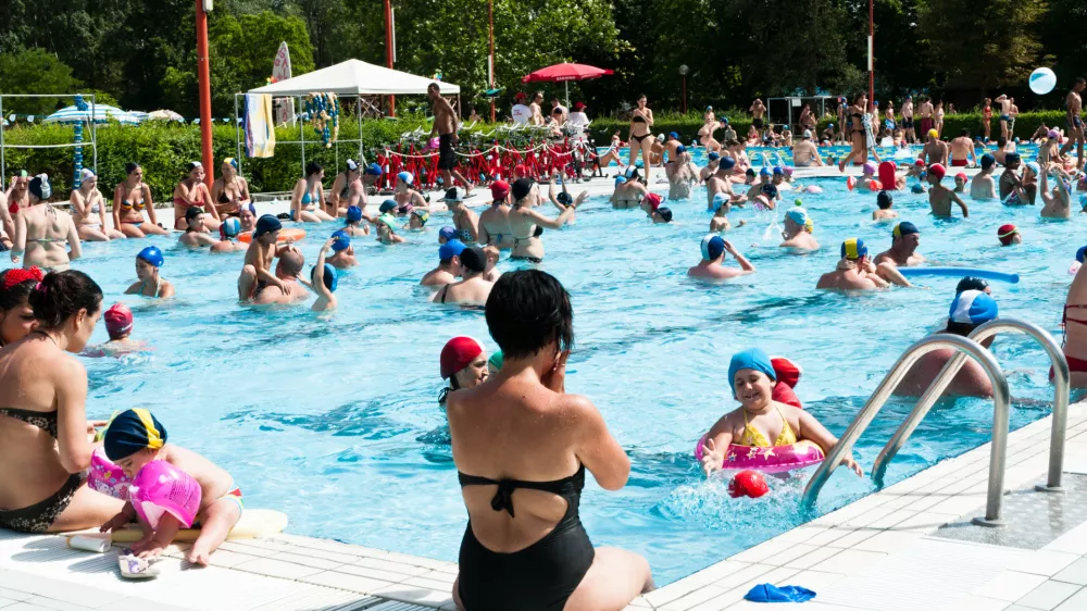 "Bologna, Italy - July 1, 2012: Adulta and families with children refreshing themself and having fun in a crowded swimming pool near Bologna (Italy). It's a sunny day, during a very hot summer."