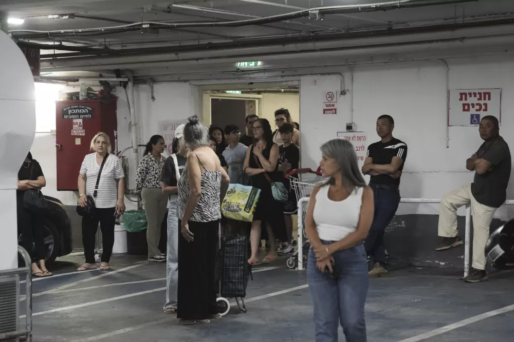 Israelis take shelter in an underground parking lot as a siren sounds a warning following a missiles that were launched from Iran, in Jerusalem, Sunday, June 15, 2025. (AP Photo/Mahmoud Illean)