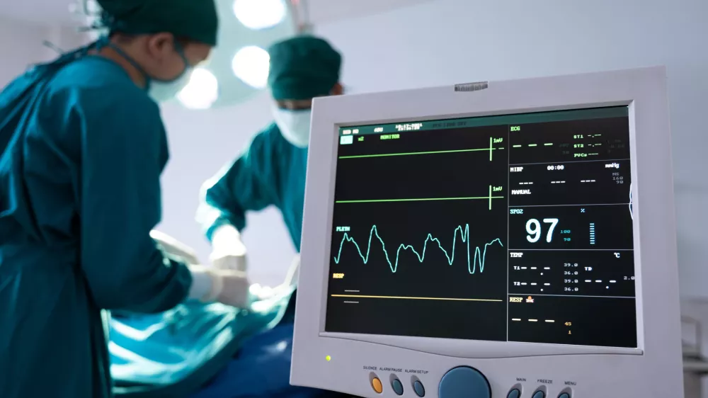 Selective at monitor and nurse using defibrillator to pump at chest of unconscious with low heart rate patient to save life while doing medical surgery inside of operating room. Emergency CPR.