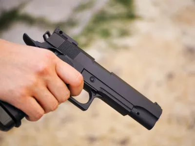 Realistic black airsoft gun in person hand. Close-up
