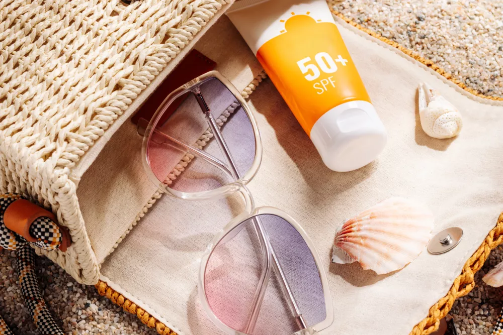 Sunscreen and glasses in a wicker straw bag on a sandy beach / Foto: Lyalya Go