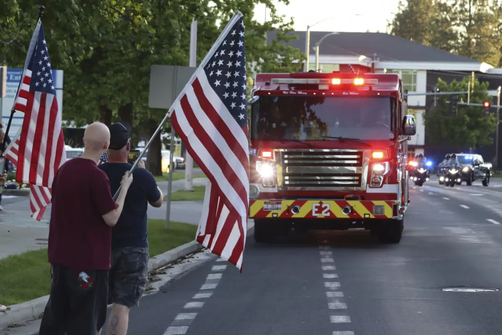 A procession from Kootenai Health headed to Spokane after a few firefighters were killed Sunday, June 29, 2025, when they were ambushed by sniper fire while responding to a blaze in a northern Idaho mountain community, in Coeur d'Alene, Idaho. (Bill Buley/Coeur D'Alene Press via AP)