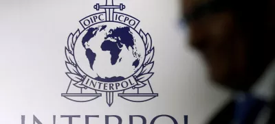 FILE PHOTO: A man passes an Interpol logo during the handing over ceremony of the new premises for Interpol's Global Complex for Innovation, a research and development facility, in Singapore September 30, 2014. REUTERS/Edgar Su//File Photo