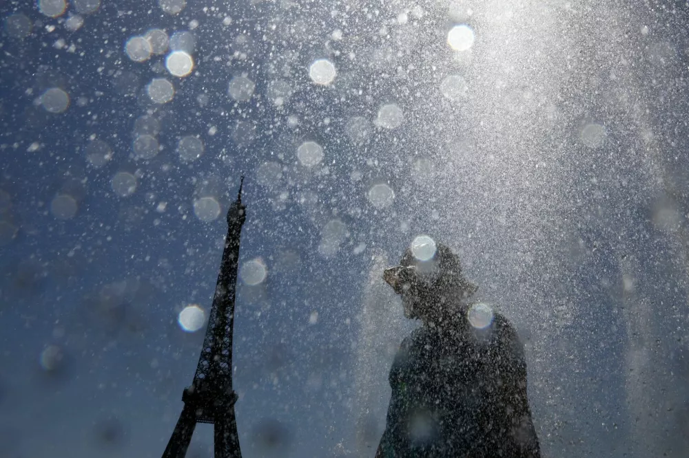 A tourist cools off in the Trocadero Fountain next to the Eiffel Tower as an early summer heatwave hits Paris, France, July 1, 2025. REUTERS/Tom Nicholson