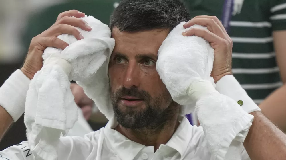 Novak Djokovic of Serbia places a cold towel around his head during a change of ends break against Alexandre Muller of France during their first round men's singles match at the Wimbledon Tennis Championships in London, Tuesday, July 1, 2025. (AP Photo/Kin Cheung)
