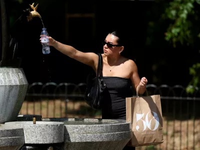 A woman fills her water bottle at a fountain in Green Park as an amber heat warning was issued in London, Britain, June 30, 2025.  REUTERS/Kevin Coombs