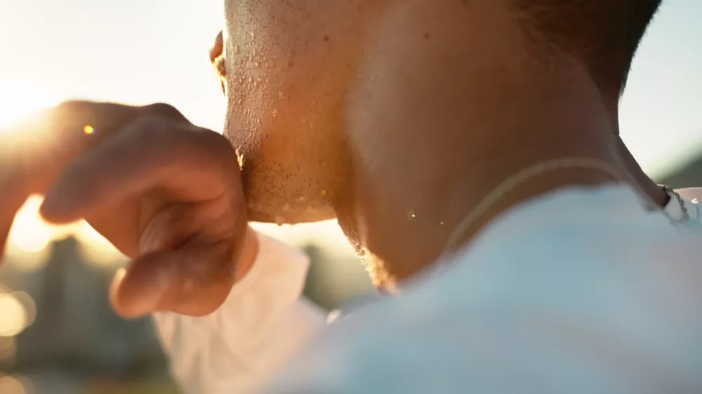 Chin, hand and sweating with sports person outdoor in nature closeup for exercise or fitness. Cardio, challenge and intense with athlete wiping perspiration from skin for marathon training or workout / Foto: Jacob Wackerhausen