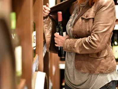 shoplifting - a woman steals a bottle of wine in a supermarket / Foto: Industryview
