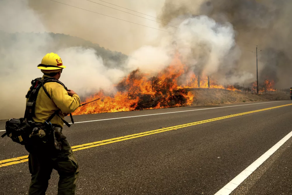 A firefighter battles the Madre Fire as it makes a run along Highway 166, Thursday, July 3, 2025, in San Luis Obispo County, Calif. (AP Photo/Noah Berger)