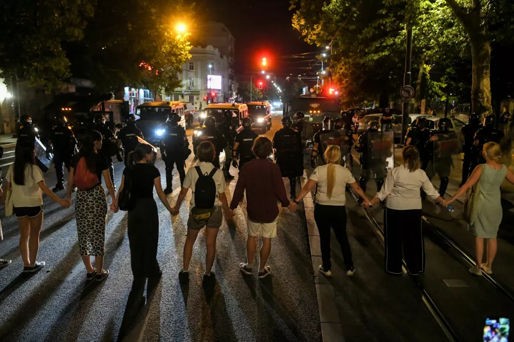Law enforcement officers stand guard opposite people holding hands during road blockades organised by students and anti-government demonstrators demanding snap elections and release of arrested protestors, in Belgrade, Serbia, July 3, 2025. REUTERS/Amir Hamzagic