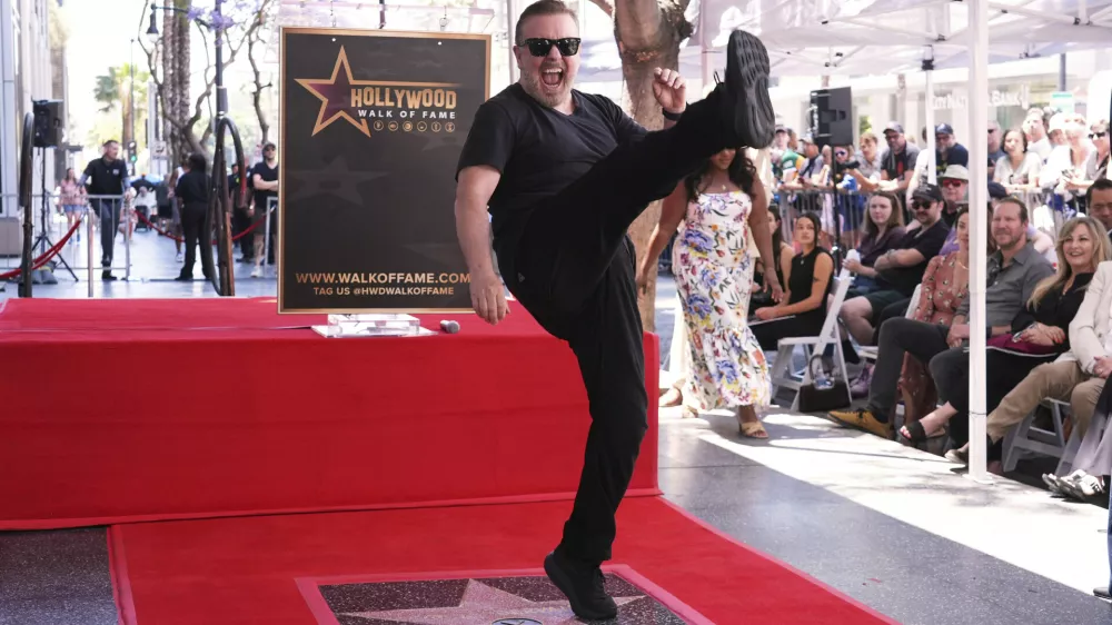Comedian Ricky Gervais celebrates with a kick at a ceremony honoring him with a star on the Hollywood Walk of Fame on Friday, May 30, 2025, in Los Angeles. (AP Photo/Chris Pizzello)