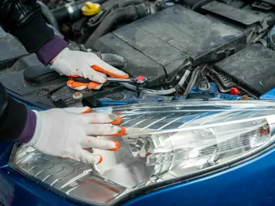 a man in gloves looks under the hood of an open car for a breakdown. Concept of owner and car breakdown