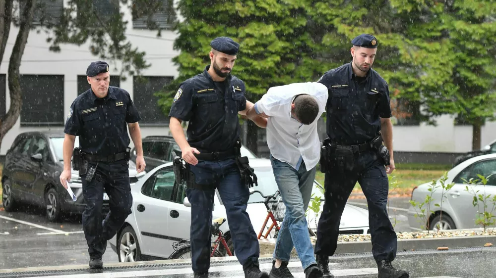 Emanuel Rep v spremstvu policistov na zaslišanje v Varaždinu. Sumijo ga umora mame s sekiro ter poskusa umorov polbrata in očima. 