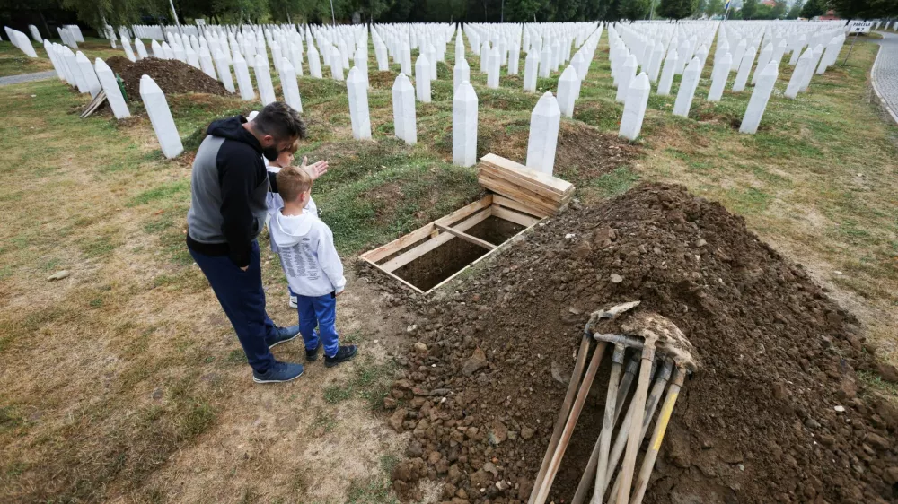 Aljo Mujcic, a Bosnian man, shows his sons a spot dug ahead of a mass funeral marking the 30th anniversary of the Srebrenica genocide, at the Srebrenica-Potocari Memorial Center in Potocari, near Srebrenica, Bosnia and Herzegovina, July 10, 2025. REUTERS/Amel Emric