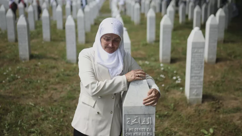 A woman holds a gravestone at the Memorial Center in Potocari, Bosnia, Friday, July 11, 2025. (AP Photo/Armin Durgut)