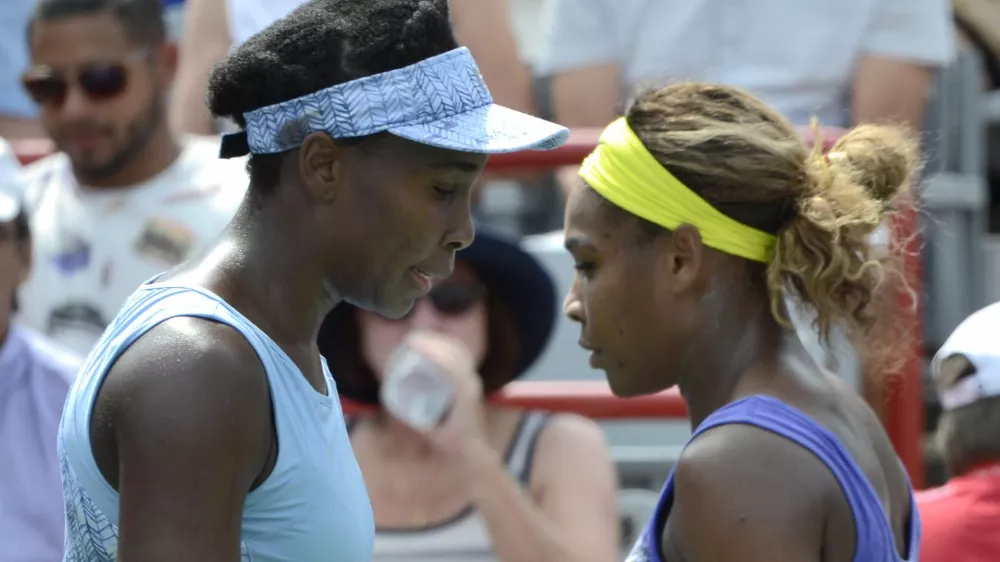 Venus Williams, left, and her sister Serena walk to their seats between games during semifinal play at the Rogers Cup tennis tournament, Saturday, Aug. 9, 2014 in Montreal. (AP Photo/The Canadian Press, Paul Chiasson)