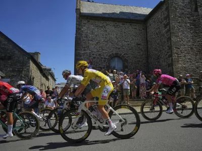 Ireland's Ben Healy, right in pink jersey, follows Slovenia's Tadej Pogacar, wearing the overall leader's yellow jersey, during the eighth stage of the Tour de France cycling race over 171.4 kilometers (106.5 miles) with start in Saint-Meen-le-Grand and finish in Laval Espace Mayenne, France, Saturday, July 12, 2025. (AP Photo/Thibault Camus)