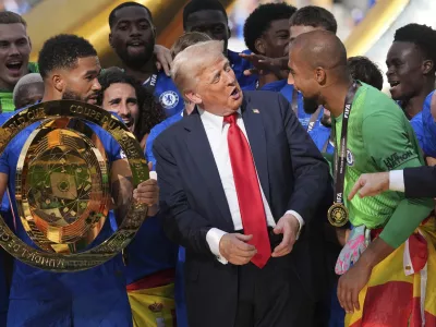 President Donald Trump, center, speaks with Chelsea's goalkeeper Robert Sanchez, right, as Chelsea's Reece James (24) holds the championship trophy following the Club World Cup final soccer match between Chelsea and PSG at MetLife Stadium in East Rutherford, N.J., Sunday, July 13, 2025. (AP Photo/Jacquelyn Martin)