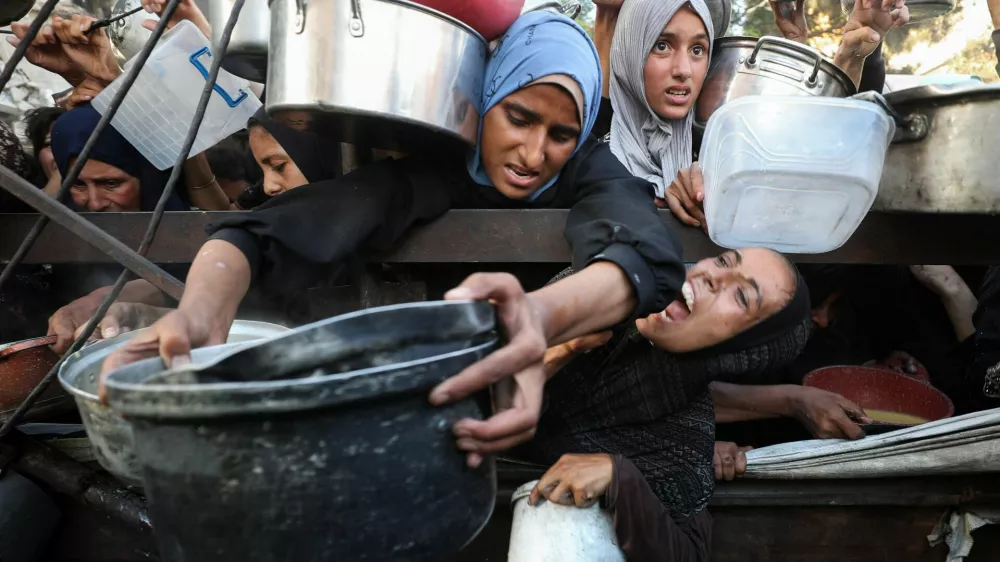Palestinians react as they ask for food from a charity kitchen, amid a hunger crisis, in Gaza City, July 14, 2025. REUTERS/Mahmoud Issa