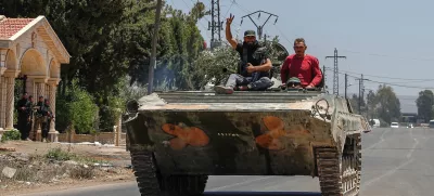 Syrian government forces sit on their armored personnel carrier, as they withdraw from Sweida city, southern Syria, Tuesday, July 15, 2025.(AP Photo/Ghaith Alsayed)