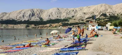 Baska, Krk, Croatia - July 6, 2012: People with their beach towels on the 1,800-meter-long Baška beach (the Vela plaža, or "Great Beach") in this resort located on the SE of the Island of Krk.