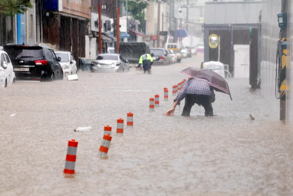 A man makes his way through a flooded street, caused by torrential rain, in Gwangju, South Korea, July 17, 2025.  Yonhap via REUTERS  THIS IMAGE HAS BEEN SUPPLIED BY A THIRD PARTY. NO RESALES. NO ARCHIVES. SOUTH KOREA OUT. NO COMMERCIAL OR EDITORIAL SALES IN SOUTH KOREA.   TPX IMAGES OF THE DAY